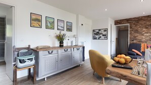 A modern kitchen with a dining area, featuring a wooden dining table, a baby high chair, and a grey cabinet with handles. - Le Château D'Ancelle (Ancelle)