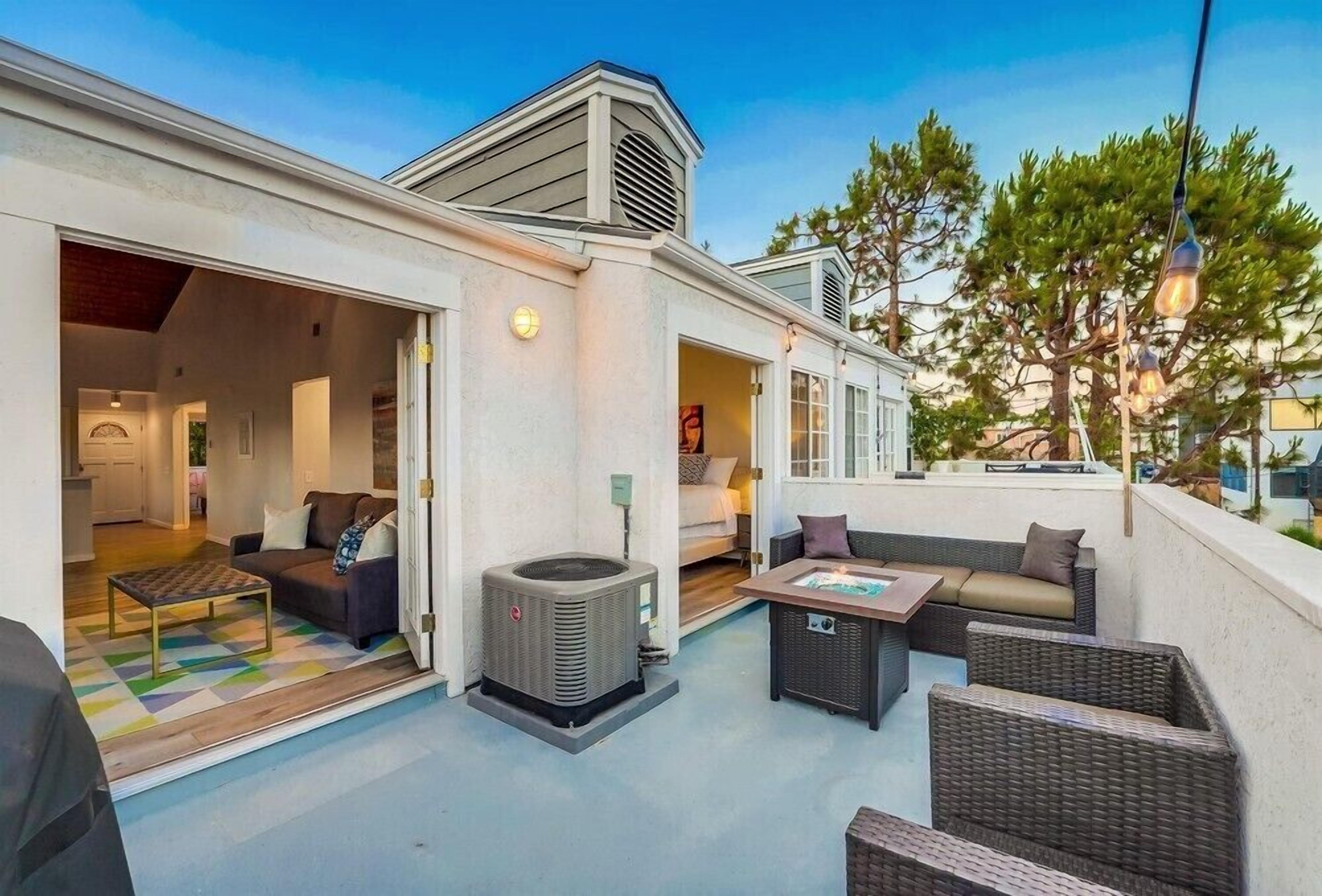 A covered outdoor living area with a sofa, a table, and an air conditioning unit.
