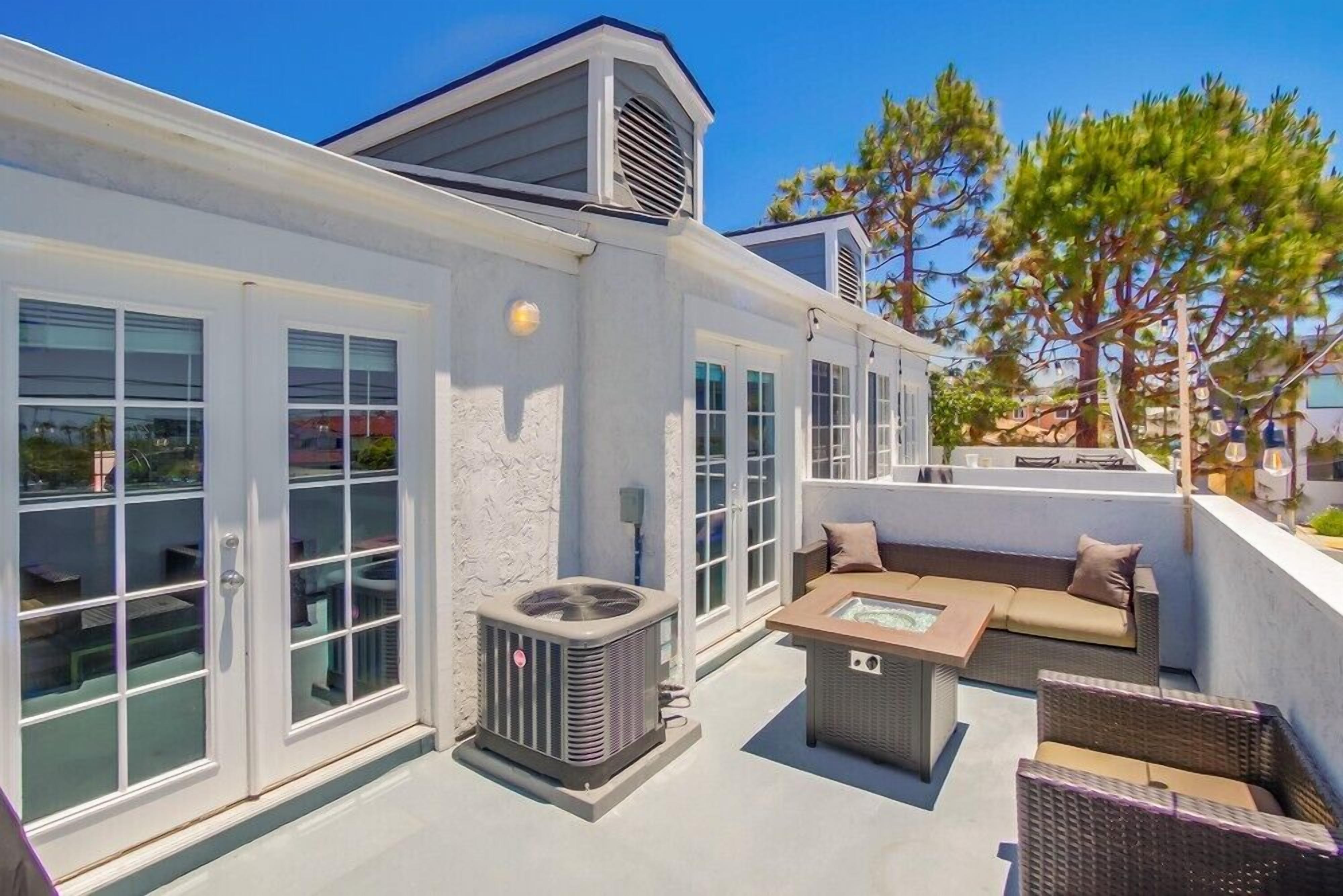A rooftop patio with outdoor furniture, a glass door entrance, and an air conditioning unit.