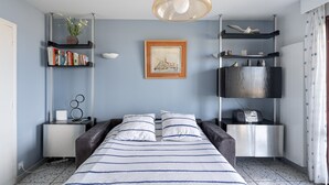 Ein Schlafzimmer mit einem Bett, Nachttischen, einem Bücherregal, einem gerahmten Bild und einer Pendelleuchte.