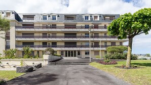 Ein mehrgeschossiges Wohngebäude mit einem zentralen Eingang, Balkonen und einem angelegten Garten.