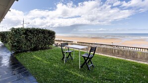Eine Terrasse mit Tisch und Stühlen mit Blick auf einen Strand.