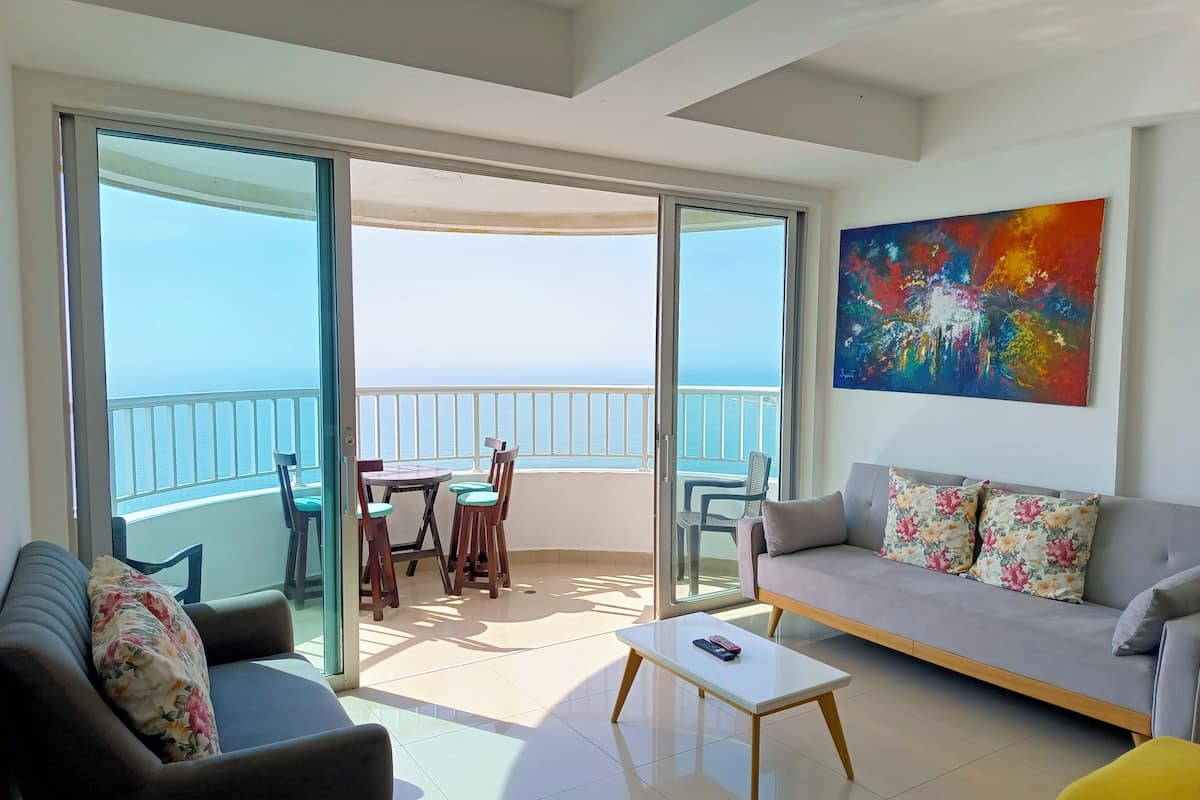 Un salon moderne avec un canapé, une table basse et un balcon offrant une vue sur la mer.