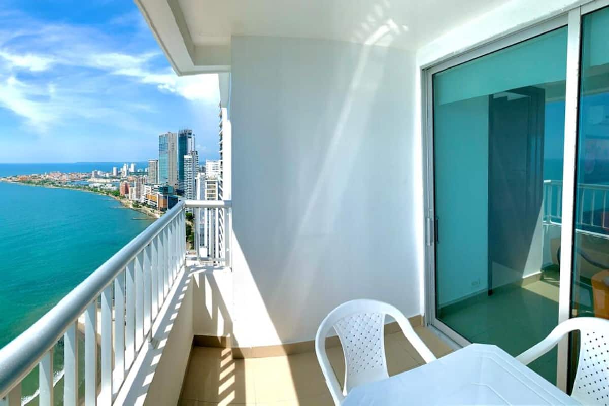Un balcon offrant une vue sur l’océan et le paysage urbain.