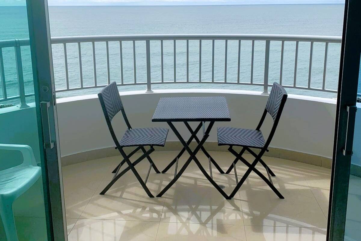 Un balcon avec une table et des chaises, offrant une vue sur la mer.