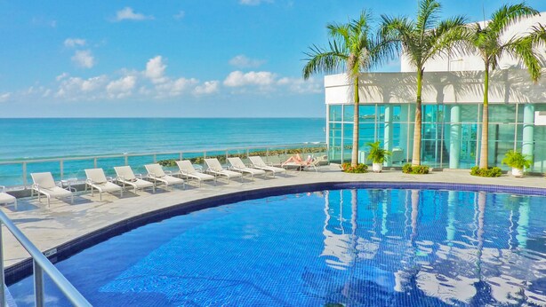 A poolside area with lounge chairs and a view of the ocean. - Apartamentos | Frente al Mar + Primera Linea de Playa | Piscina TOP (Cartagena)