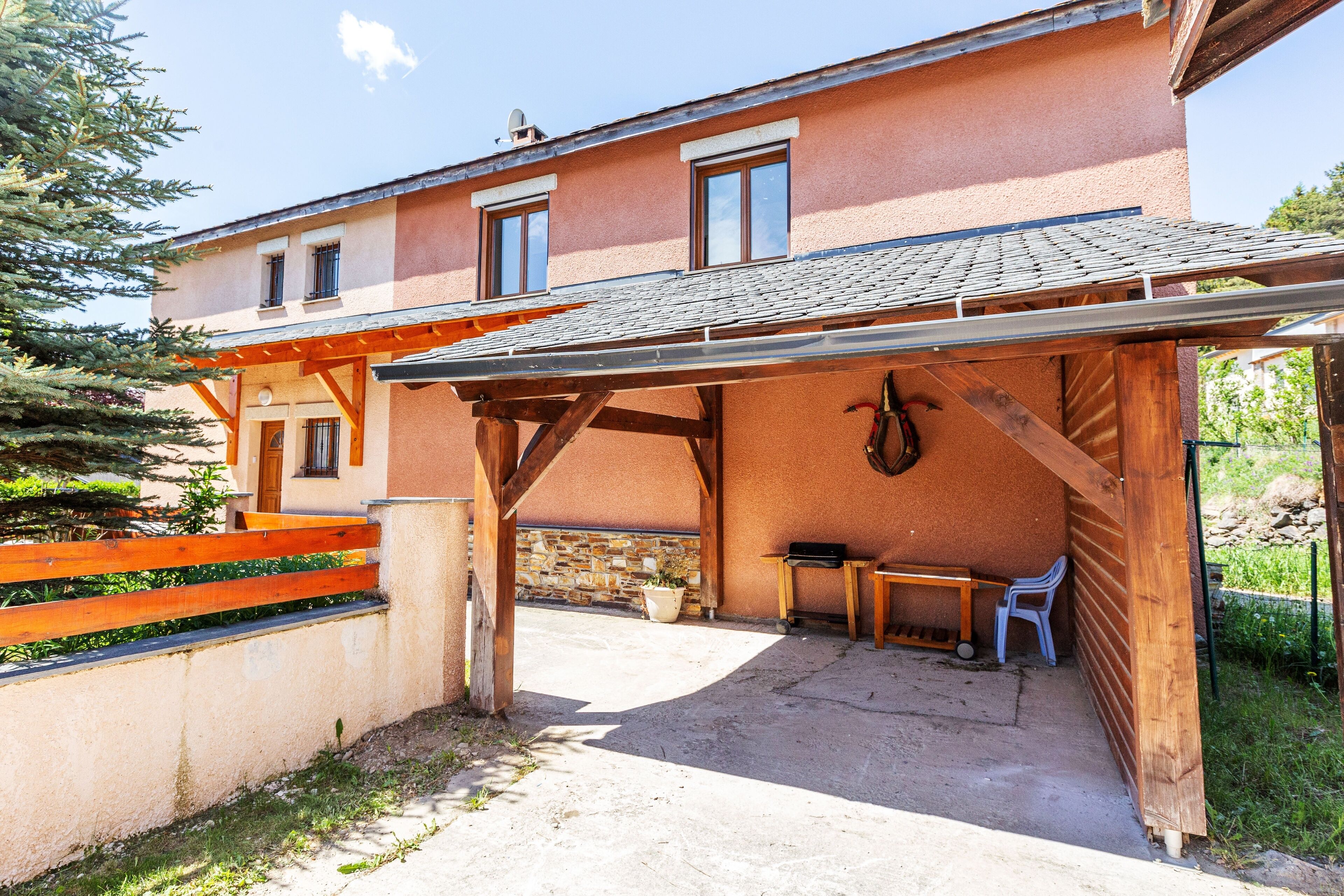 A building with a covered patio area, a stone wall, and a wooden fence.