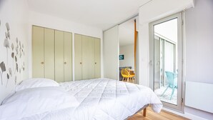 Een slaapkamer met een bed, een kledingkast en een glazen schuifdeur naar een balkon.