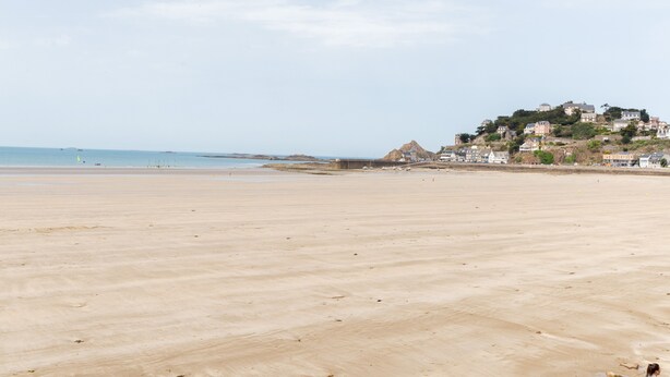 Una playa con una vista distante de una colina con edificios.