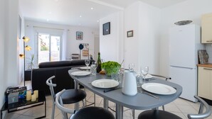 Una cocina moderna con una mesa de comedor preparada para cuatro personas, un refrigerador y un sofá al fondo.
