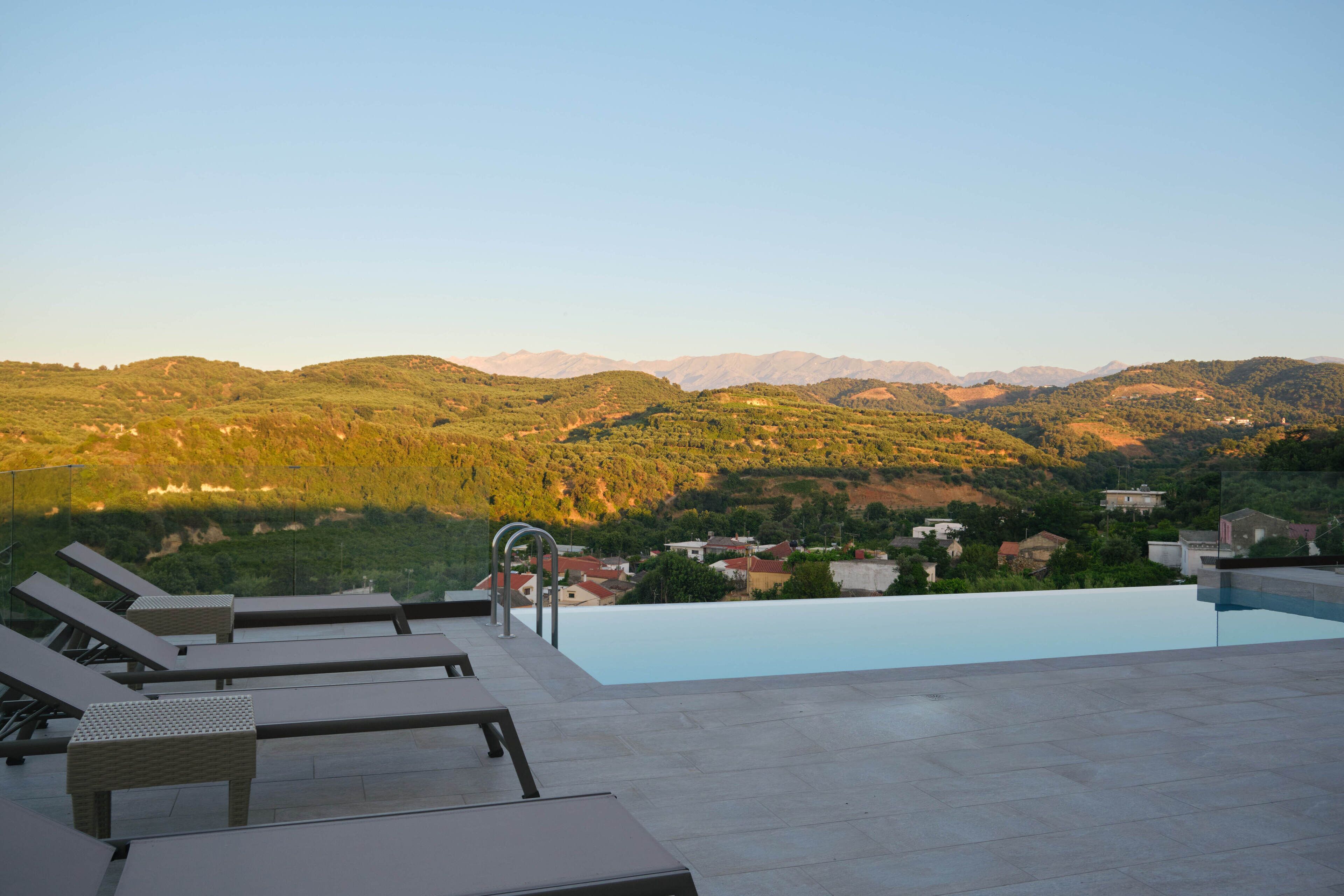 A poolside area with lounge chairs and a view of a mountainous landscape.
