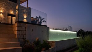 Un bâtiment moderne avec une façade en pierre, un balcon en verre et un élément décoratif aquatique.