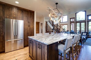 A modern kitchen with a large island, stainless steel appliances, wooden cabinets, and a unique chandelier. - X2835 | Recently Updated | Winter Shuttle | Beautifully Decorated | Hot Tub (Steamboat Springs)