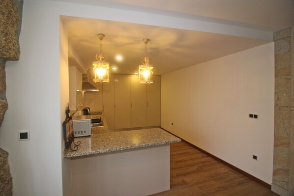 A modern kitchen with granite countertops, stainless steel appliances, and pendant lighting.