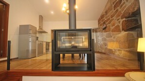 A modern kitchen with a built-in wood stove, stainless steel appliances, and a stone accent wall. - rural house in Geres for 4 people with fireplace (Gerês)