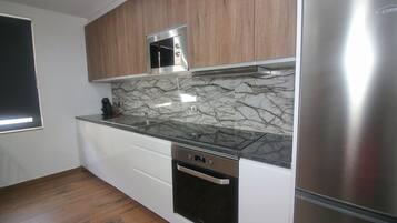 A modern kitchen with a stainless steel refrigerator, a built-in oven, and a microwave.