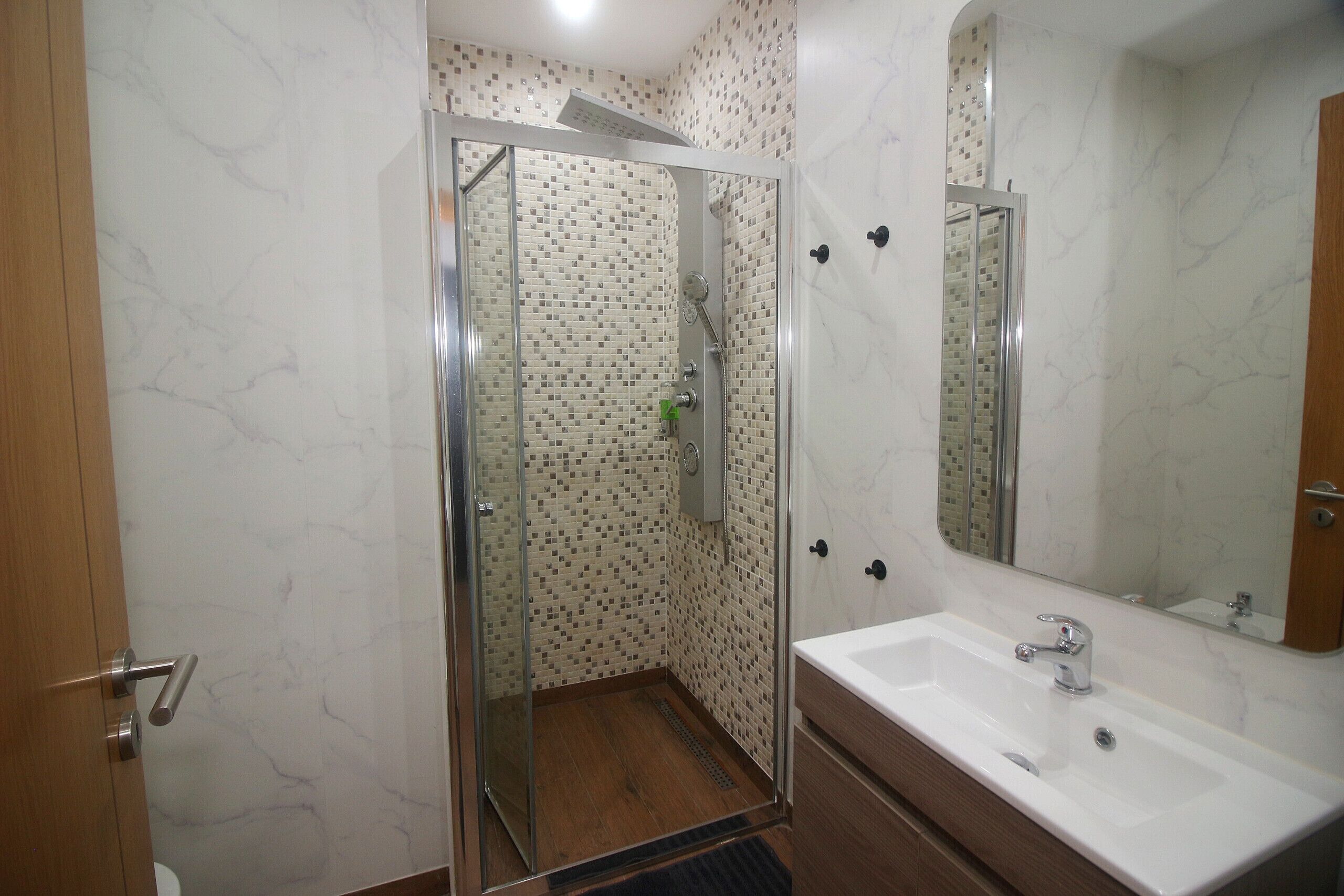 Une salle de bain avec une douche à parois de verre, un lavabo blanc et un miroir.