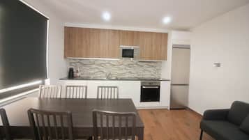 A compact kitchen with white cabinets, a marble backsplash, a built-in microwave, and a dishwasher.