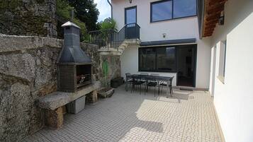 A patio with a stone wall, a chimney, and a table with chairs.