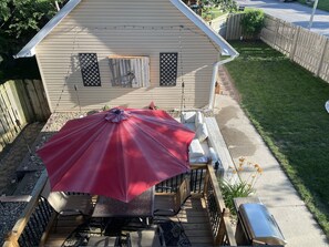 A deck with outdoor furniture, a red umbrella, and a house with a beige exterior.