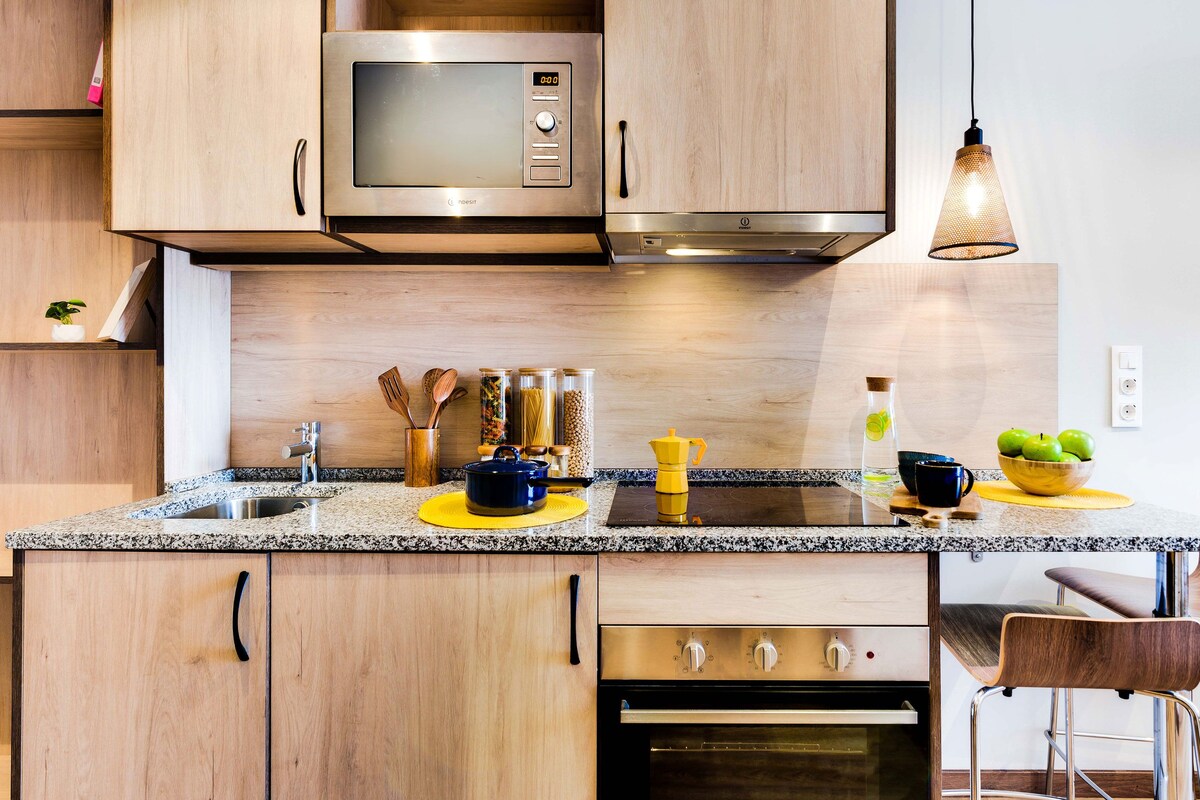 A modern kitchen with wooden cabinets, a stainless steel microwave, a built-in oven, and a granite countertop.