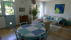 A cozy living room with a round table, a sofa, and a dining area. - Rez de Maison Avec Jardin Arboré Privatif à 1 km de la Plage (La Baule-Escoublac)