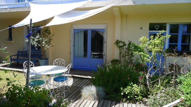 A patio with a table and chairs, a blue door, and potted plants. - Rez de Maison Avec Jardin Arboré Privatif à 1 km de la Plage (La Baule-Escoublac)