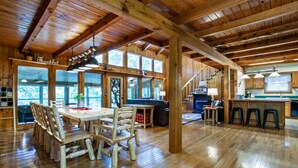 A spacious wooden interior with a dining area, kitchen, and large windows. - Quietside Cabin: Sunroom, Fire Pit, Theater Den, & Stunning Views (Walland)