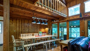 A rustic wooden interior with a large wooden dining table, benches, and a leather couch. - Quietside Cabin: Sunroom, Fire Pit, Theater Den, & Stunning Views (Walland)
