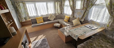 A cozy RV interior with a sofa, a small table, and a window with curtains.