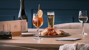 Una mesa de comedor con una botella, vasos y un plato de comida.
