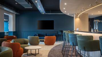 Un área de lounge moderna con asientos cómodos, un bar y un televisor de pantalla plana grande.