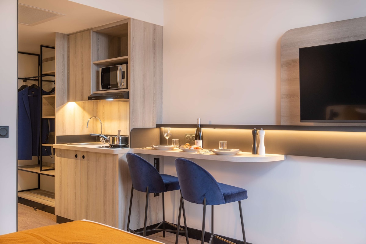 Een moderne keuken met een magnetron, spoelbak en een bar met zitplaatsen.