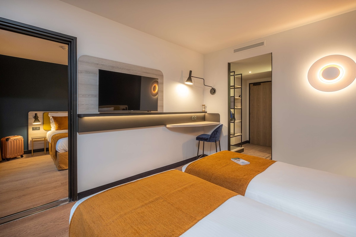 Een moderne hotelkamer met een bed, een bureau, een stoel, een televisie en een badkamer.