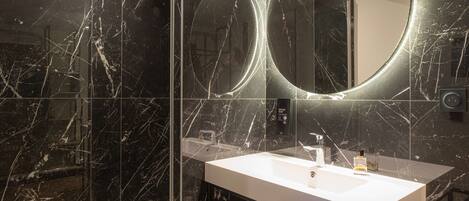 Un baño moderno con tocador de mármol, un espejo grande y una cabina de ducha de vidrio.