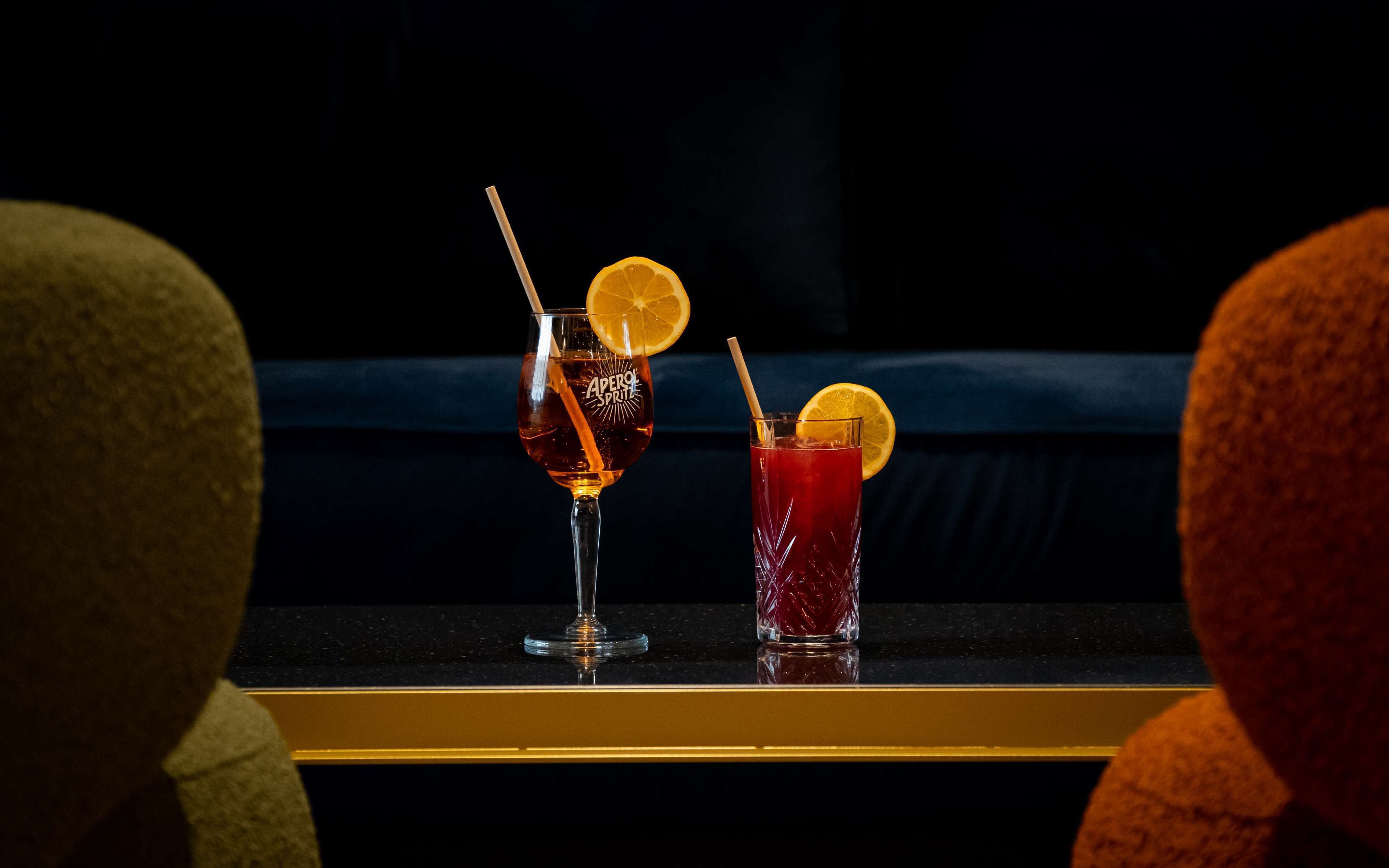 Dos bebidas sobre una superficie reflectante, sobre fondo oscuro.