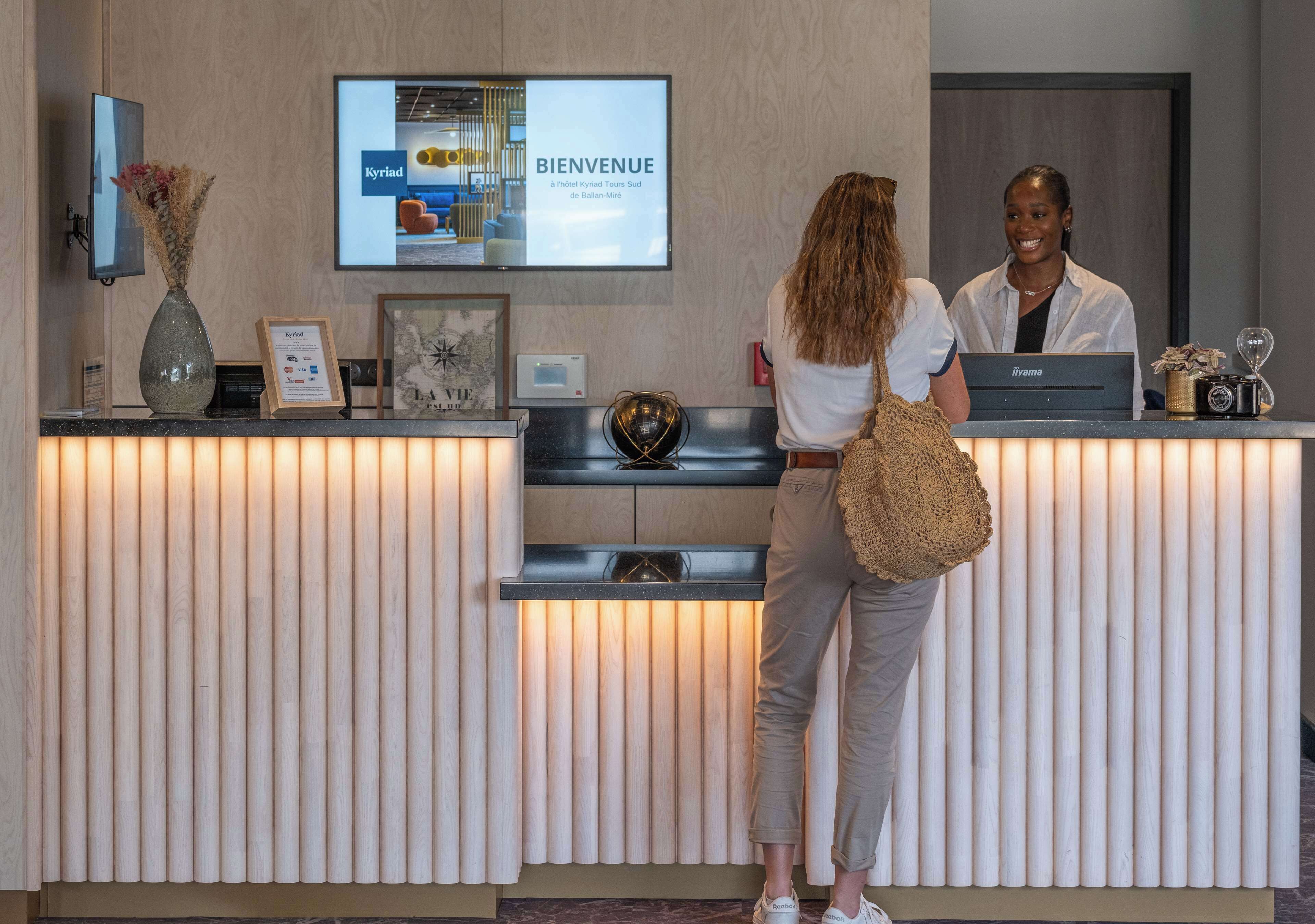 A reception desk with a digital screen displaying 'BIENVENUE' and 'A l'Institut Kryd Tours Sud de Balle-Mie'.