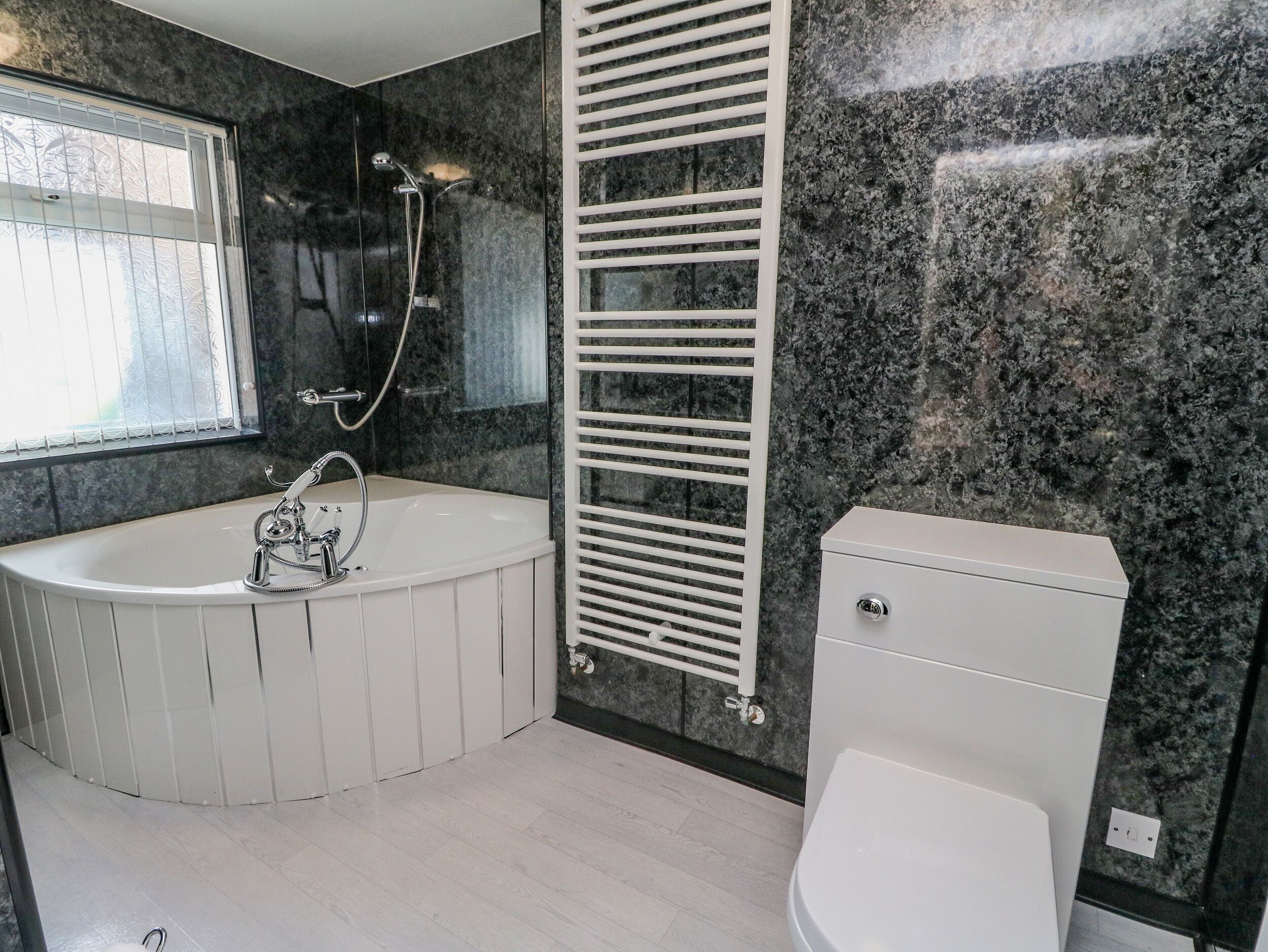 Ein modernes Badezimmer mit einer freistehenden Badewanne, einer Toilette und einer Heizkörper.