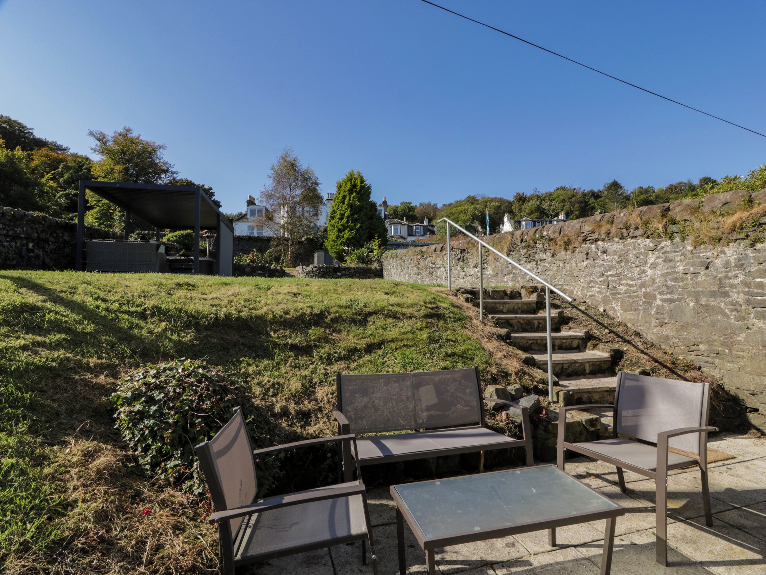 En terrasse med udendørs møbler, en stentrappe og en stenvæg.