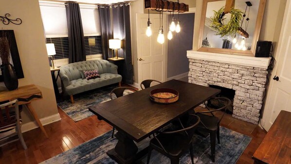 Un comedor con una mesa de madera, sillas, chimenea y sofá.