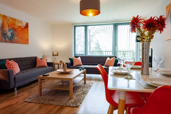 Un salon moderne avec un canapé, une table basse et une table à manger dressée pour le repas.