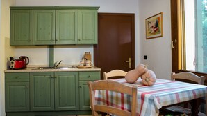 Una cucina con mobili verdi, un lavello e un tavolo con tovaglia a scacchi.