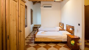 Camera da letto con due letti, mobili in legno, pavimento a scacchi e condizionatore d'aria.