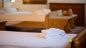 Una camera d'albergo con due letti, una testiera in legno e un mucchio di asciugamani bianchi in primo piano.