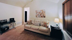 Una sala de estar con un sofá color crema, una mesita de centro, una lámpara y un cuadro en la pared.