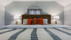 Une chambre d’hôtel avec un grand lit, deux lampes de chevet, une tête de lit en bois et une fenêtre avec des rideaux.