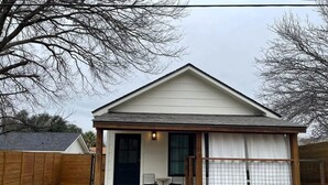 A small, single-story building with a covered porch and a sliding glass door. - Private guesthouse, Hot tub, soaking tub, In town! (Fredericksburg)