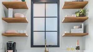 A kitchen with teal cabinets, a window, wooden shelves, and a coffee maker. - Private guesthouse, Hot tub, soaking tub, In town! (Fredericksburg)