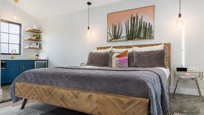 A bedroom with a bed, bedside table, and a wall-mounted artwork.