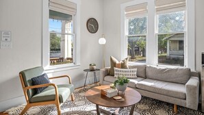 Ein Wohnzimmer mit Sofa, Ohrensessel, Couchtisch und einer Wanduhr.